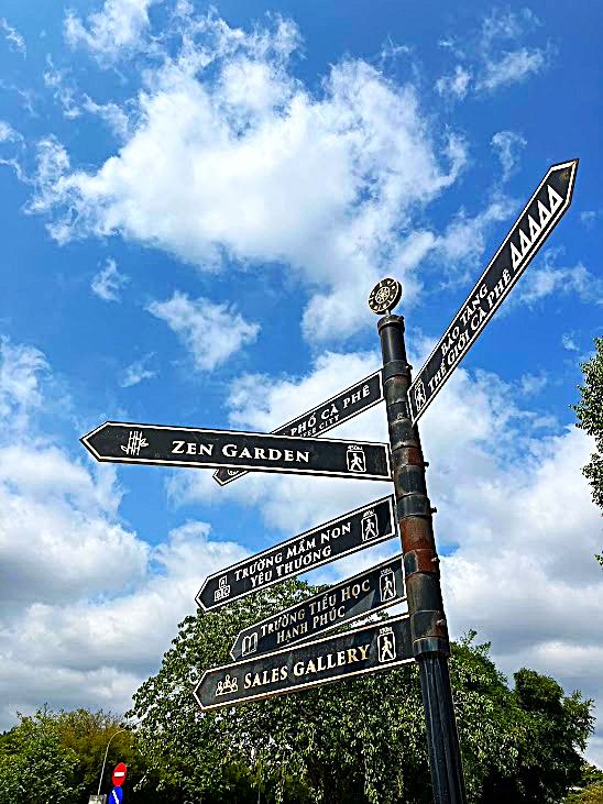 バンメトート・コーヒー村に立つZEN GARDENなど多方向の案内標識と青空